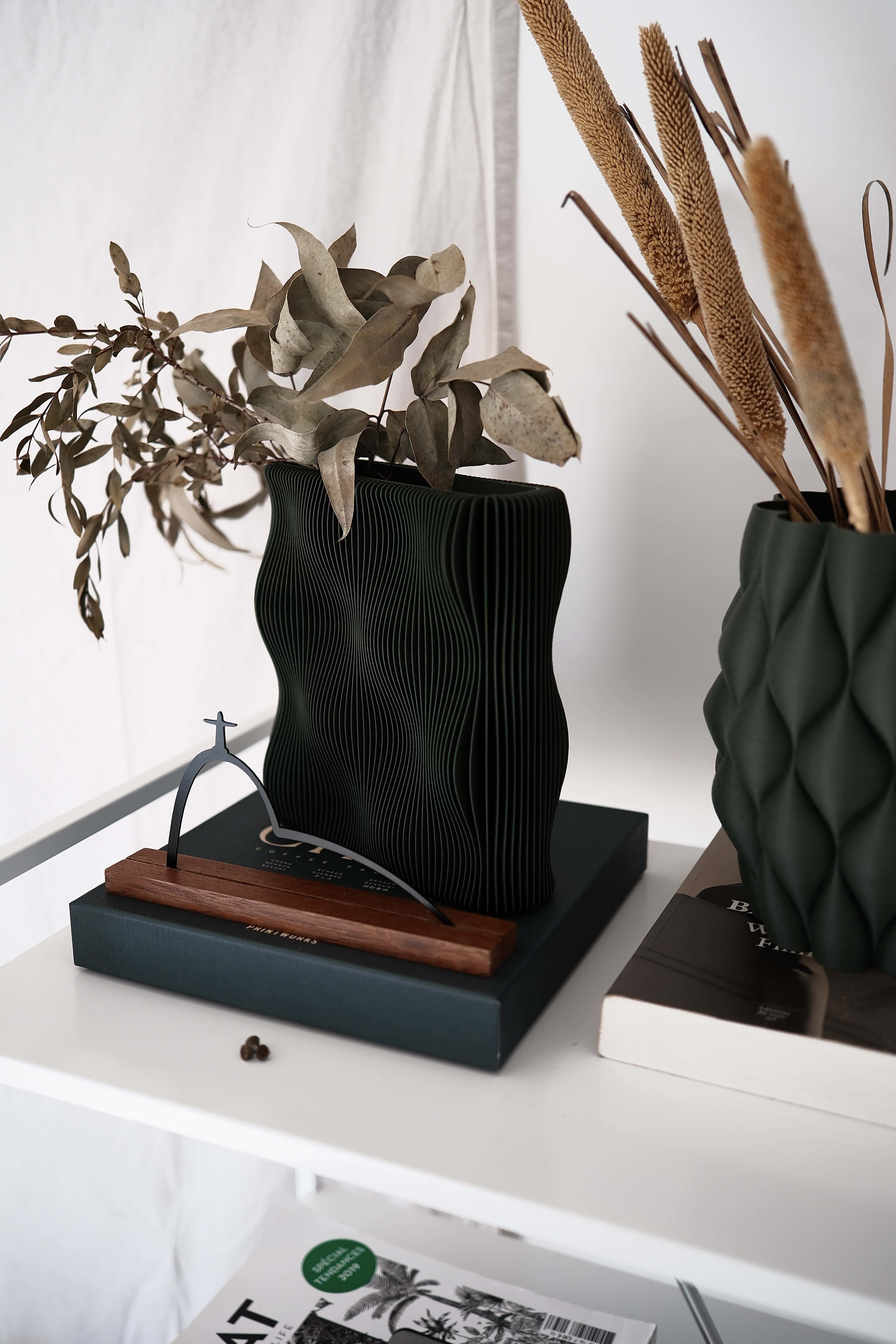 Dark green decorative vase with dried plants on a white surface #color_green