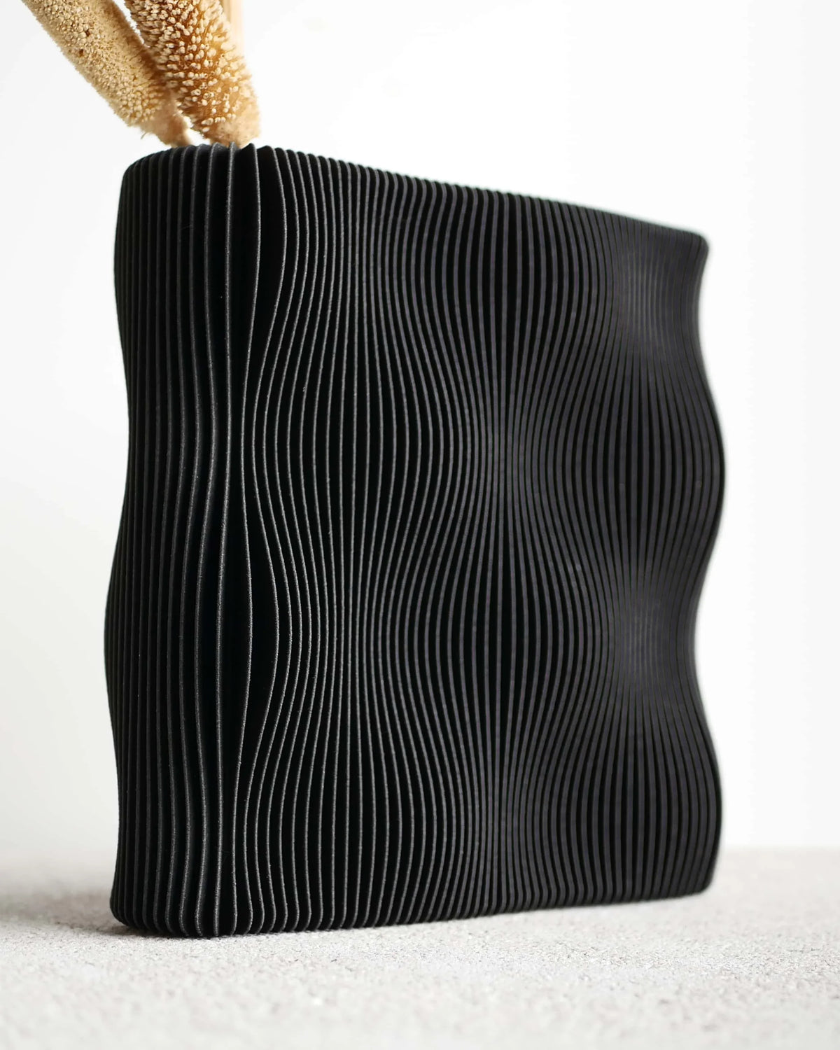TIDE vase Black close-up fine wave-ribbed texture detail, matte carbon black finish, bio-sourced wood