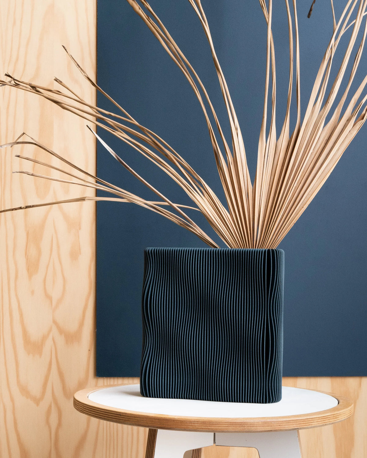 TIDE vase Blue on stool with dried palm stems, navy blue wave-ribbed texture, interior lifestyle shot