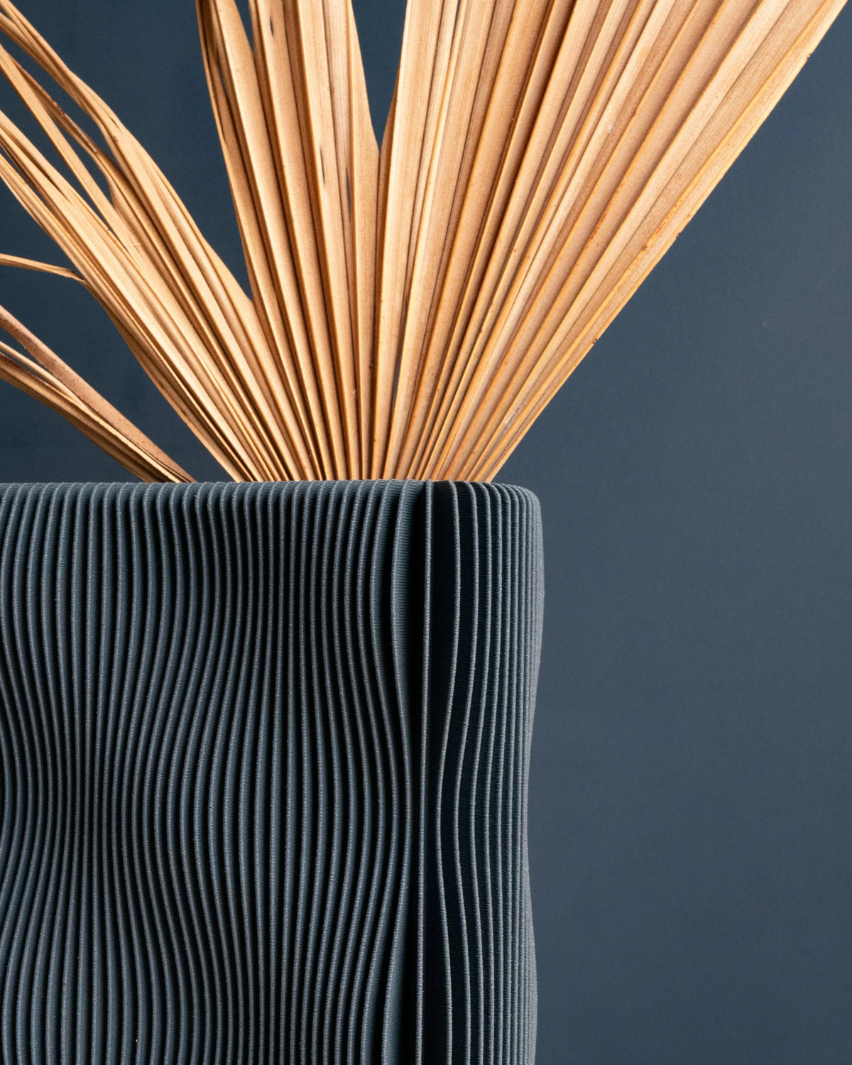 TIDE vase Blue close-up with dried palm stems, deep navy fine ribbed surface detail, bio-sourced wood