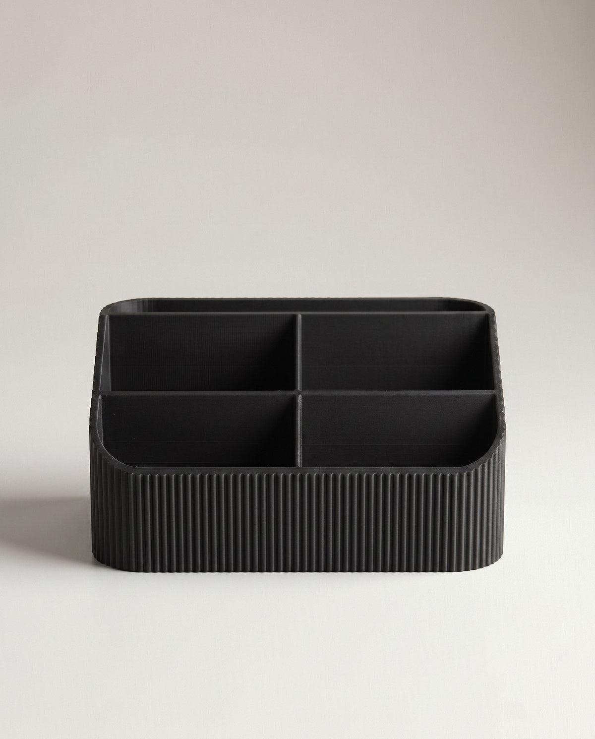 A direct, symmetrical front portrait of the empty COCO black fluted desk organizer, showcasing all five interior compartments clearly. The seamless off-white background emphasizes the uniform ribbed texture and matte black tone.