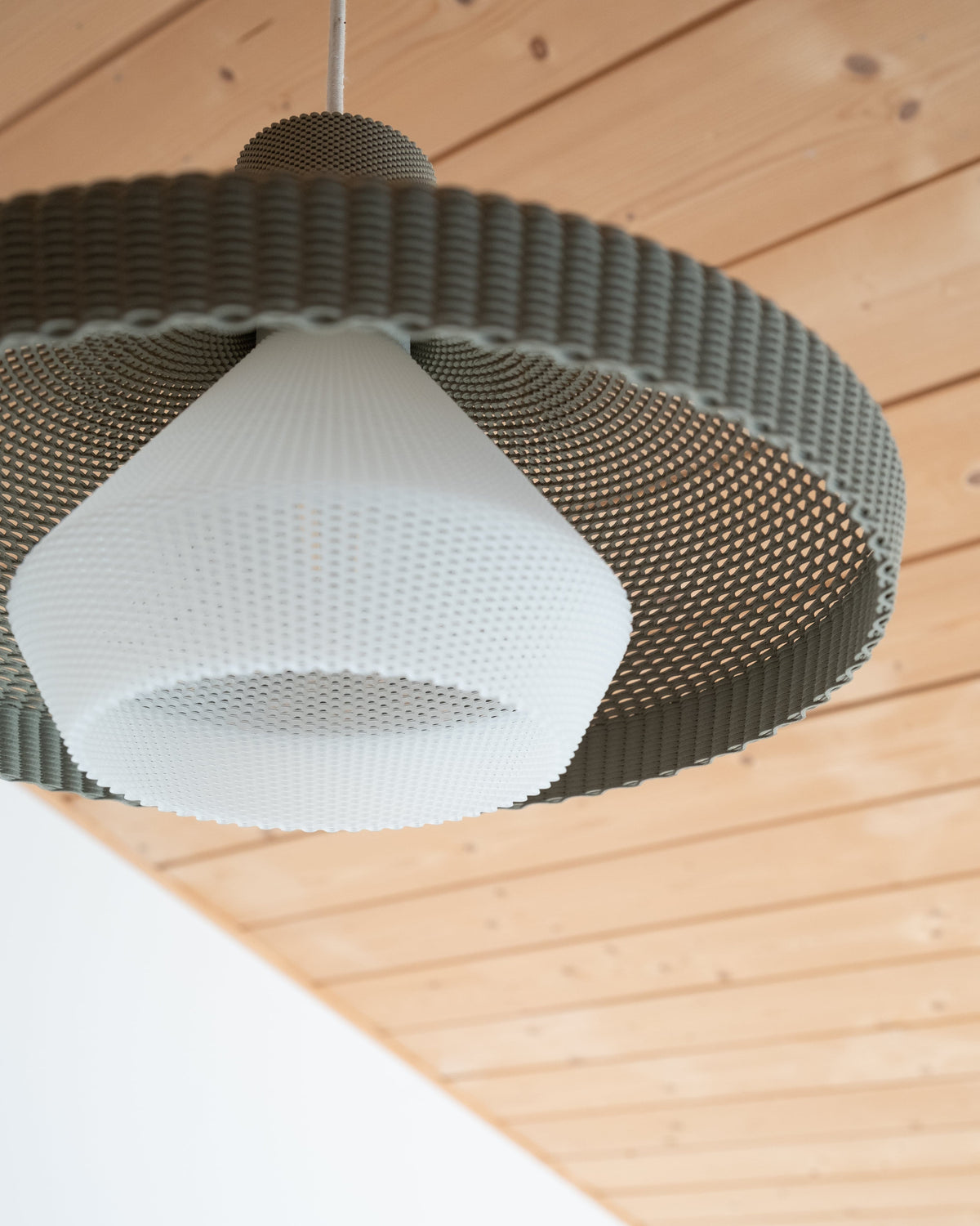 Modern pendant light with woven design on a wooden ceiling