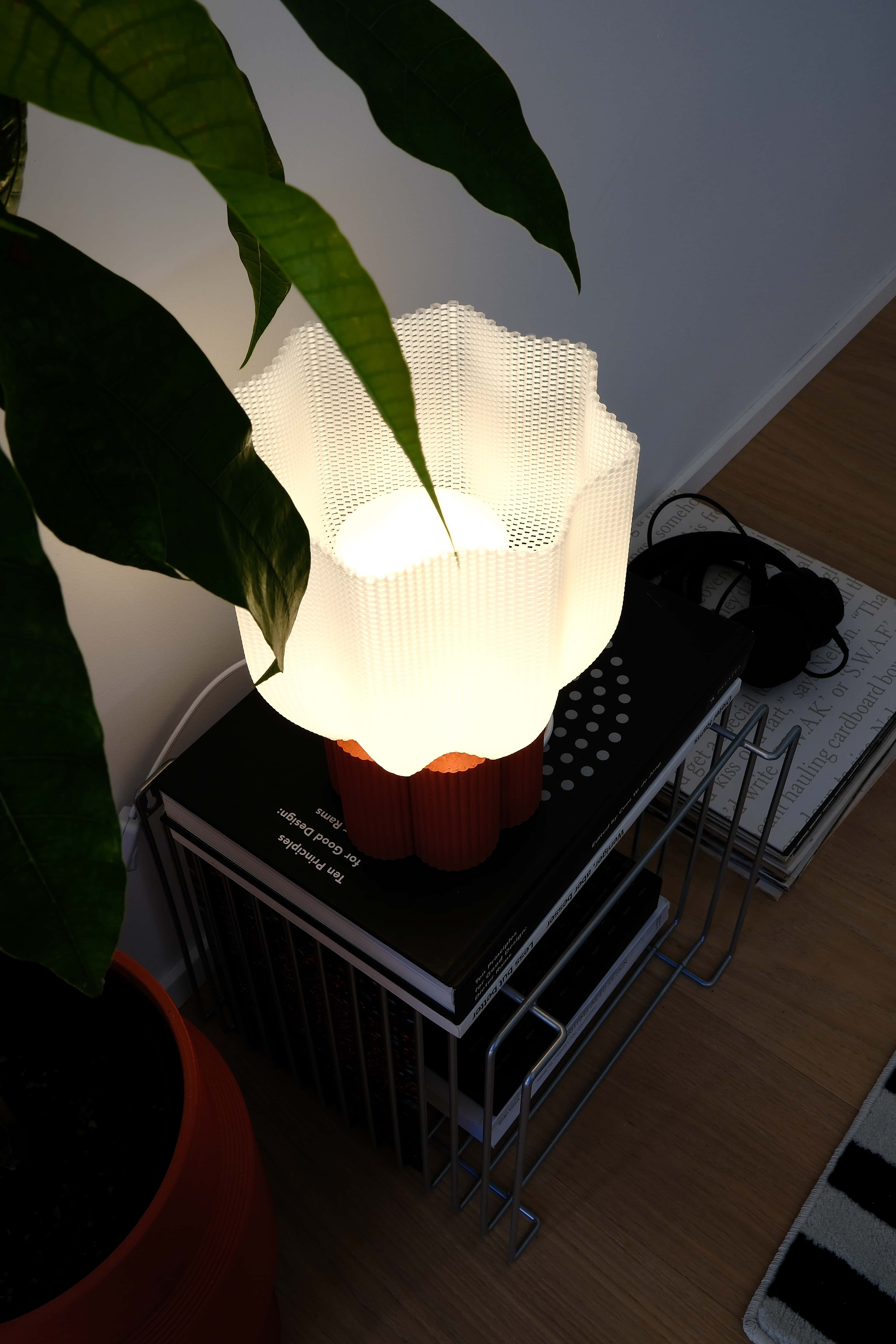Lamp with a white shade on a table next to a plant