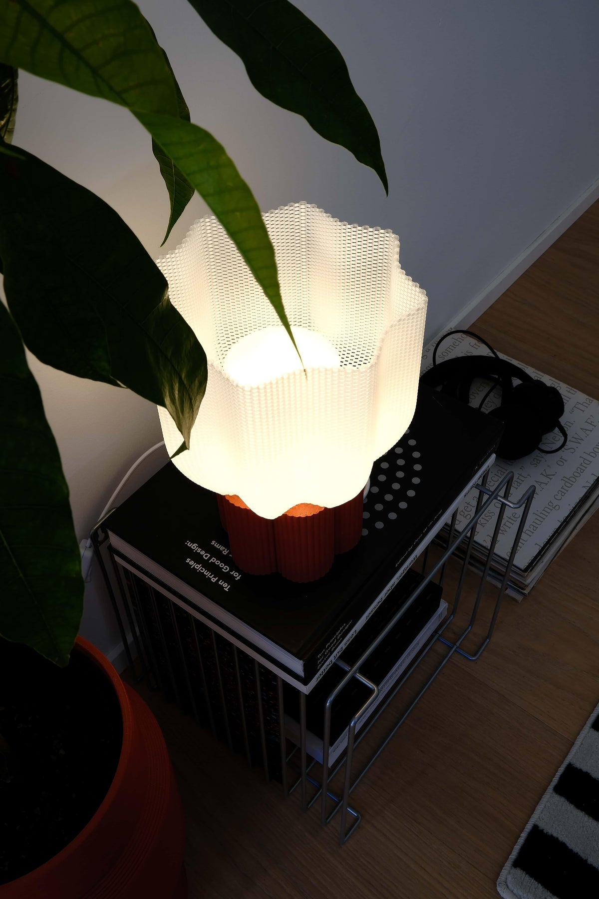Lamp with a white shade on a table next to a plant
