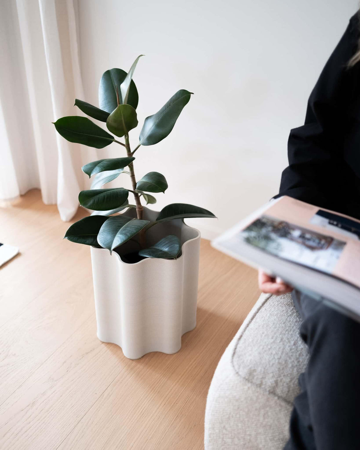 Minimalist home decor featuring the Rippled floor planter in a cozy reading nook, styled on the floor next to a person for scale.