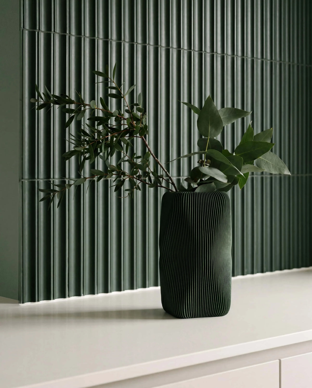 Soho sculptural vase forest green with olive branches - wave texture detail against green fluted tile wall