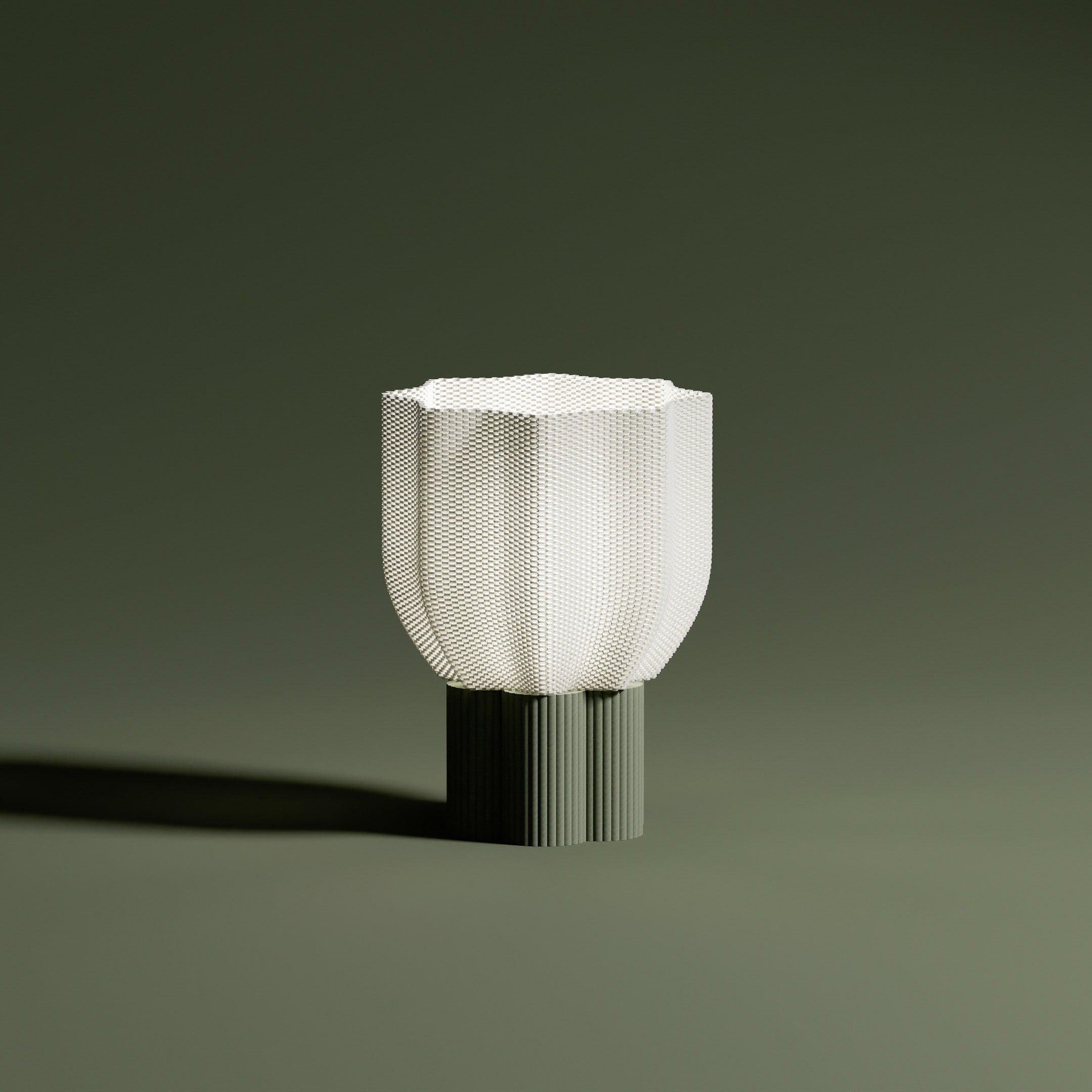 Bloom lamp lit with pleated beige base on olive green background. Warm glow and contemporary mood.