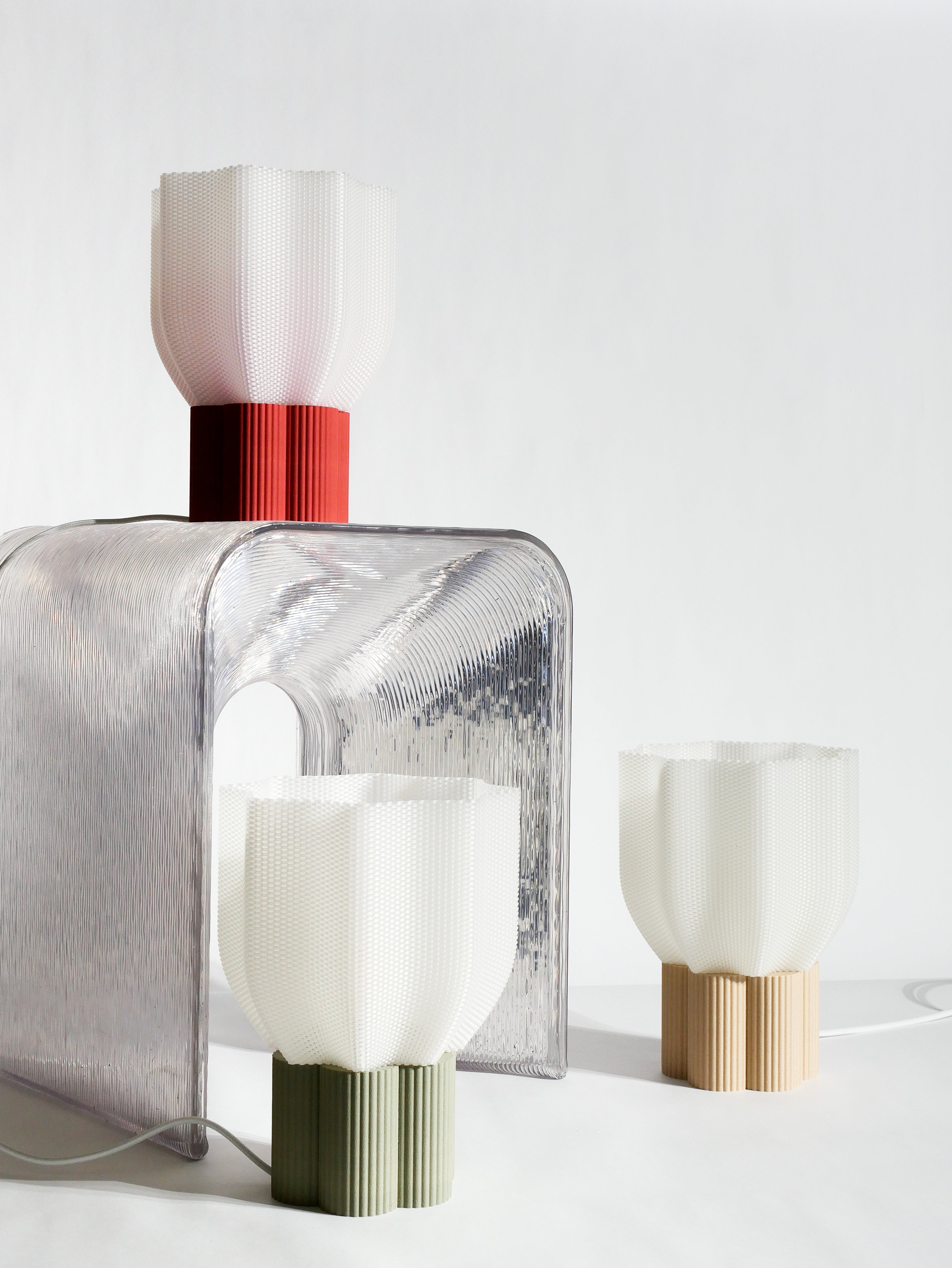 A full view of the three Bloom lamp models with different base colors (olive green, light wood, and terracotta). The white background highlights the consistency of the design and the variety of finishes. Bloom is a sustainable table lamp made in France