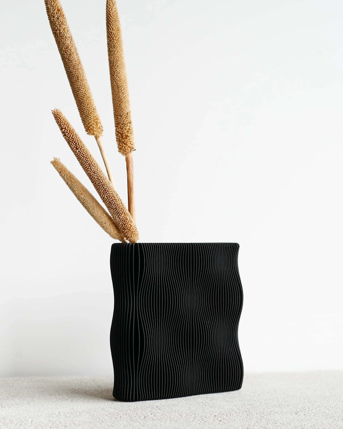 TIDE vase Black with dried cattail stems, matte wave-ribbed surface, bio-sourced wood, 22cm height