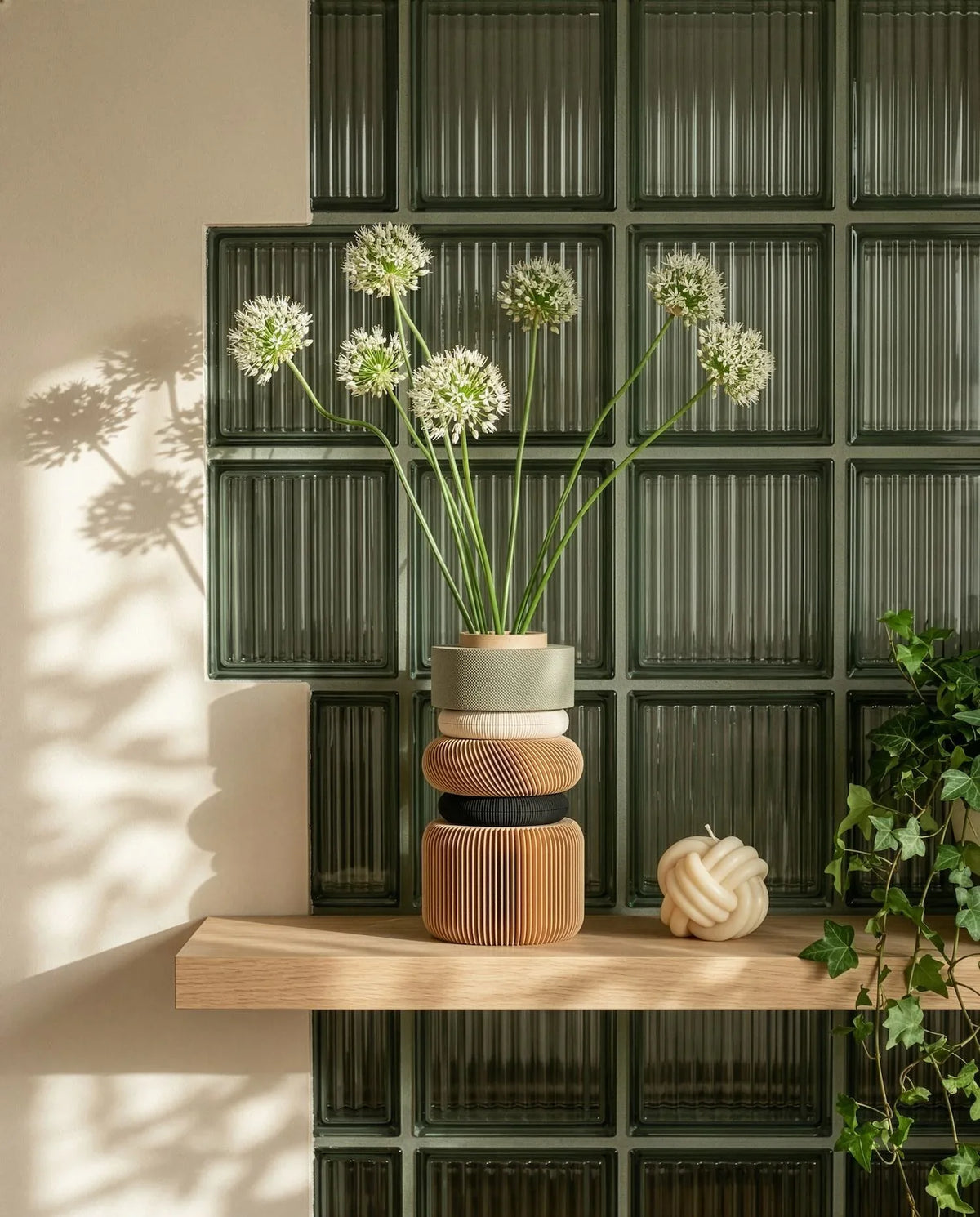 Vase with flowers on a wooden shelf against a glass block wall