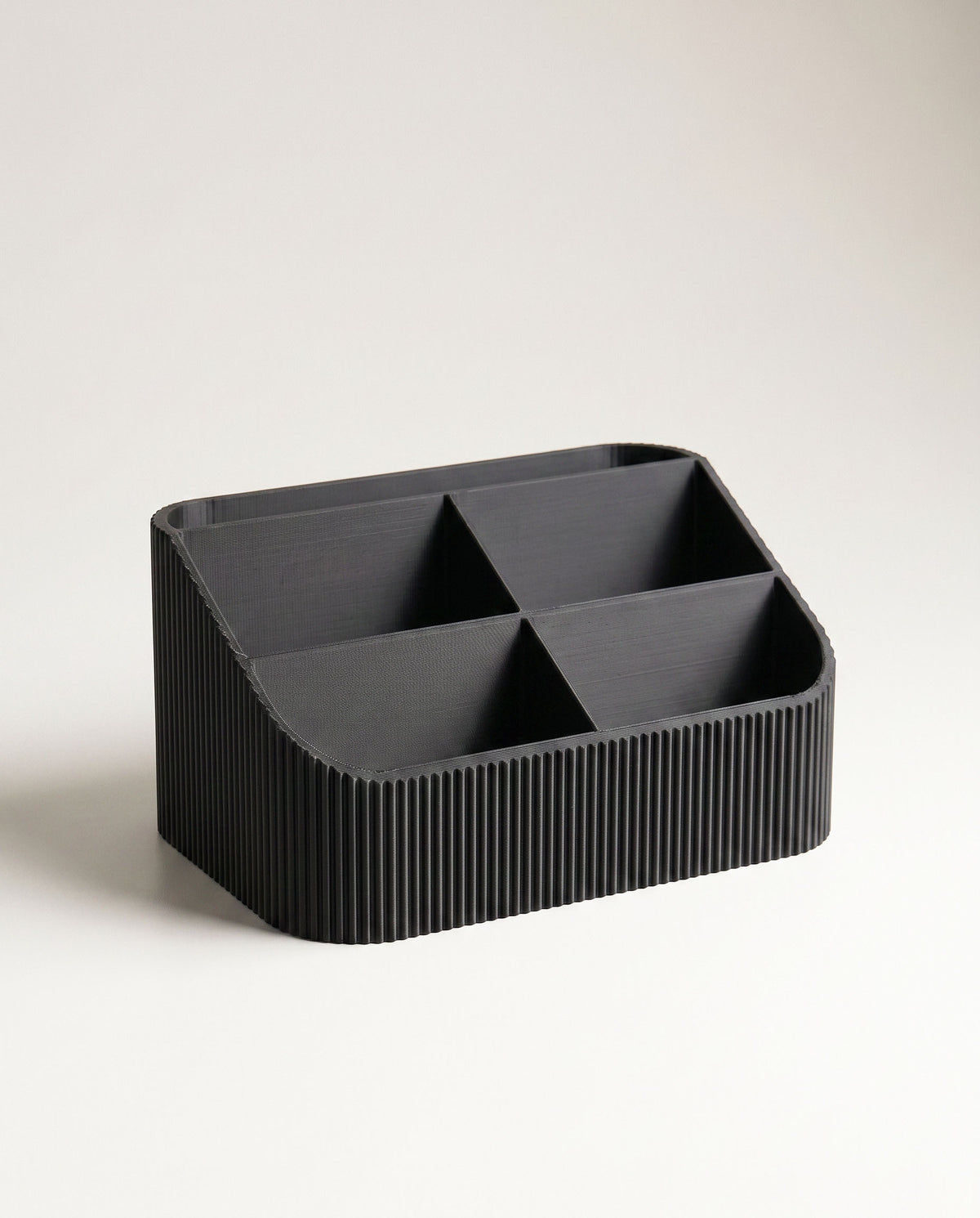 A direct, symmetrical front portrait of the empty COCO black fluted desk organizer, showcasing all five interior compartments clearly. The seamless off-white background emphasizes the uniform ribbed texture and matte black tone.