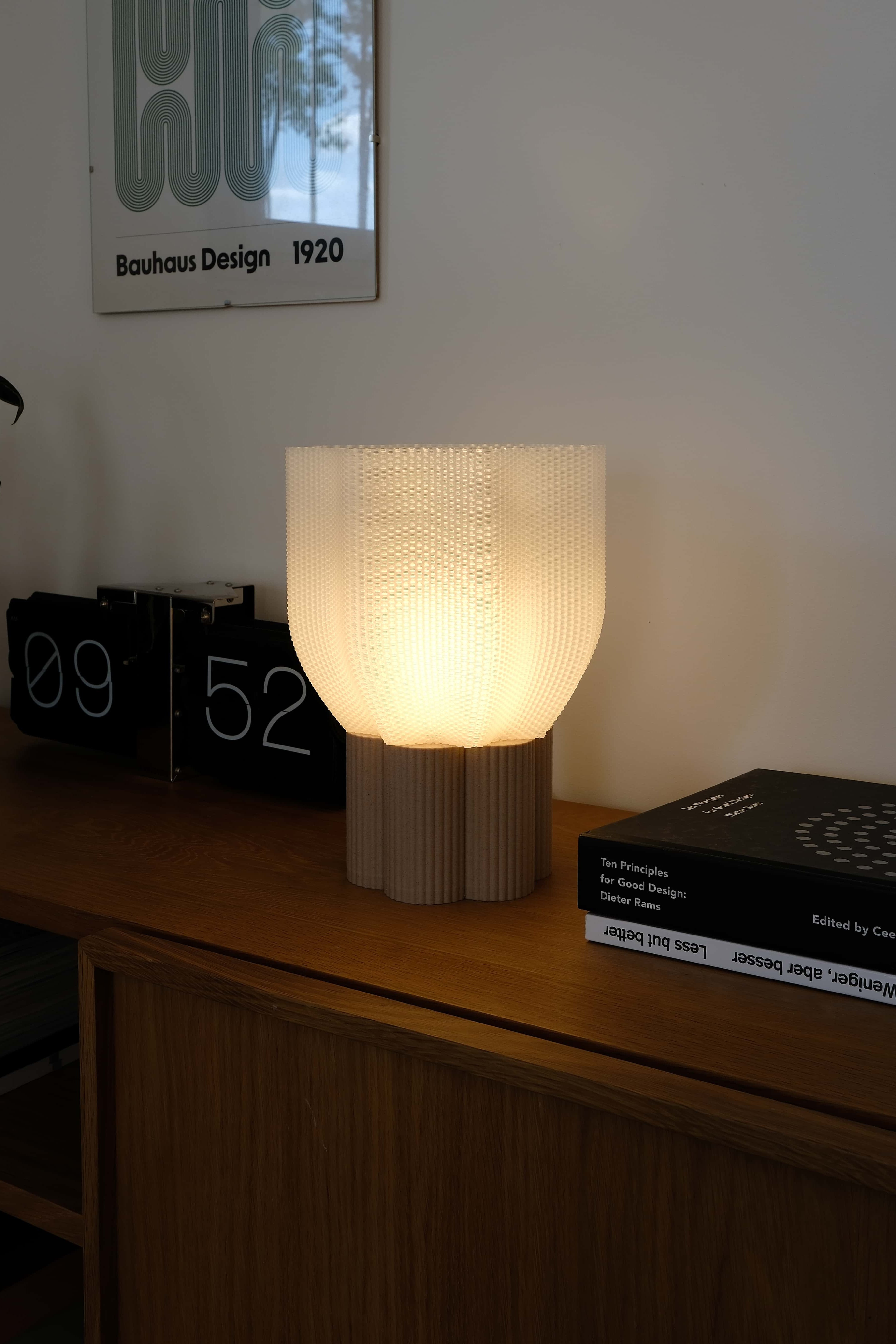 Table lamp on a wooden surface with a clock and books in the background