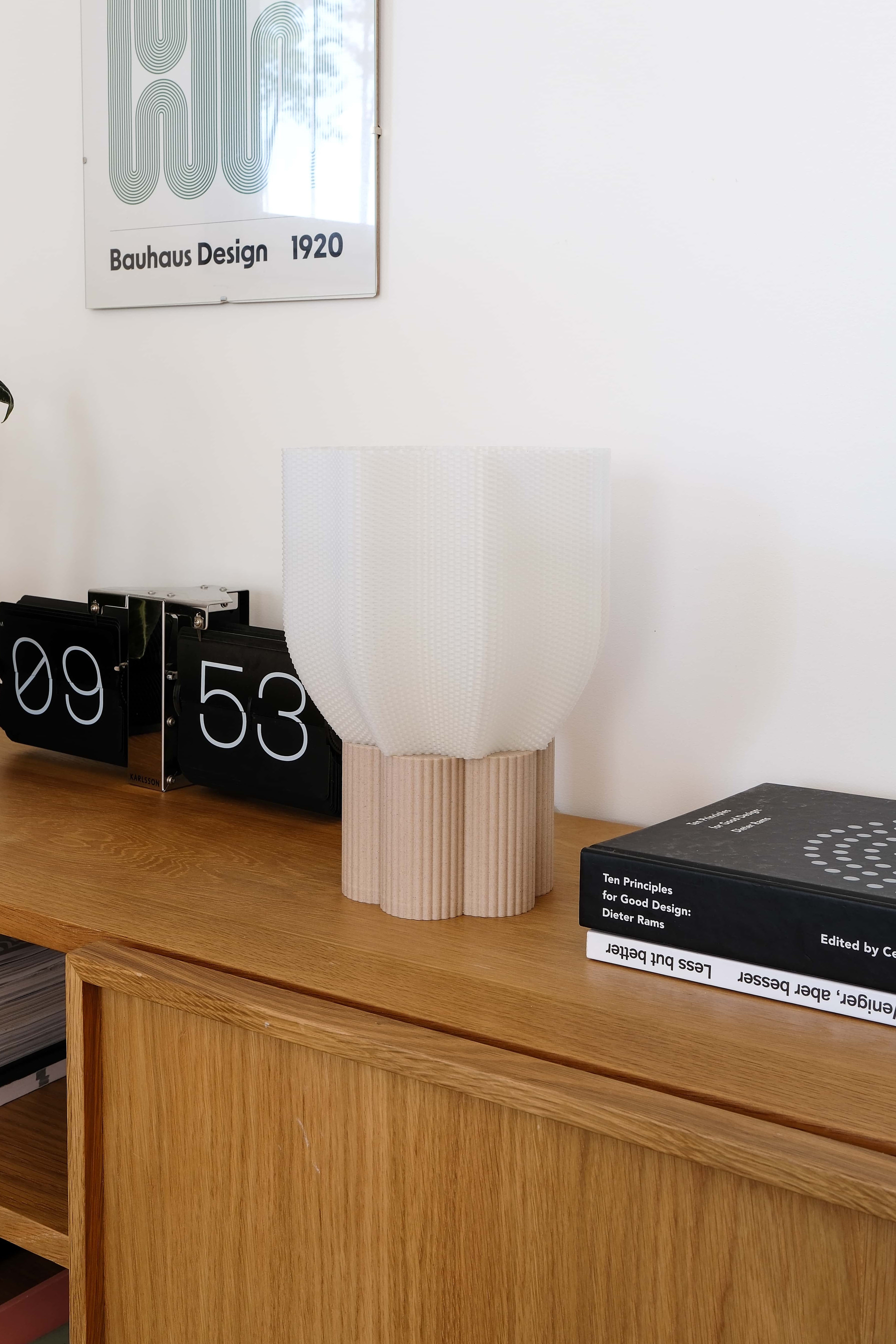 Wooden shelf with decorative items including a lamp, books, and a poster on a white wall.