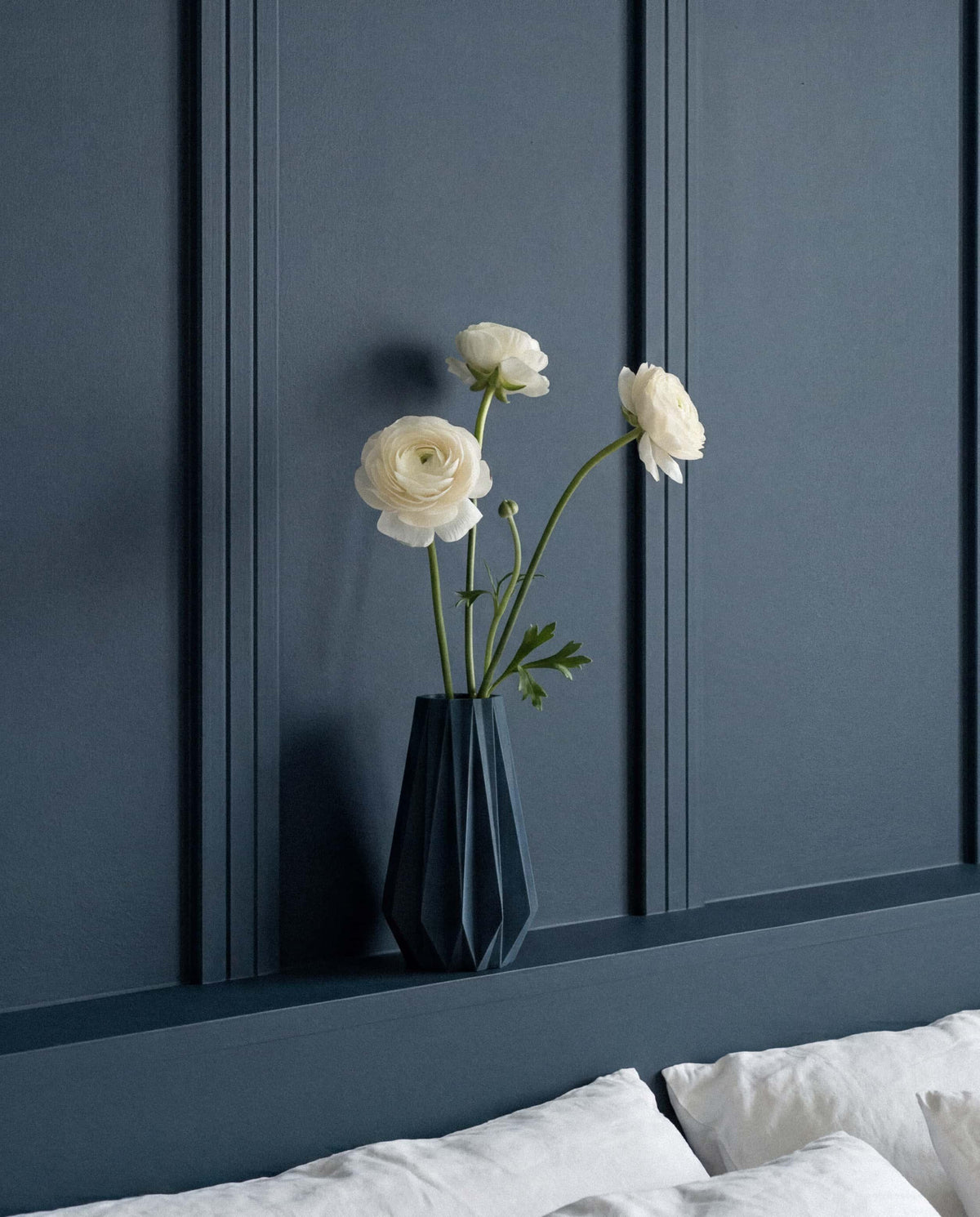 Blue origami vase with dried flower stems - dark blue interior wall styling