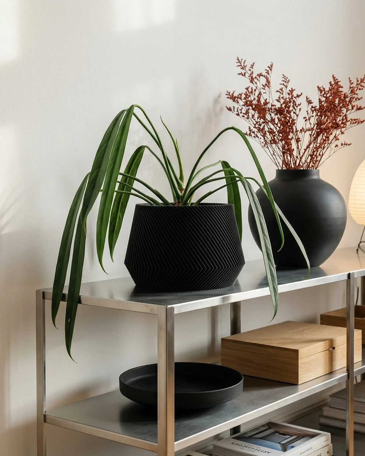 oslo black planter in Modern interior with a metal shelf holding decorative items including plants, vases, and books.