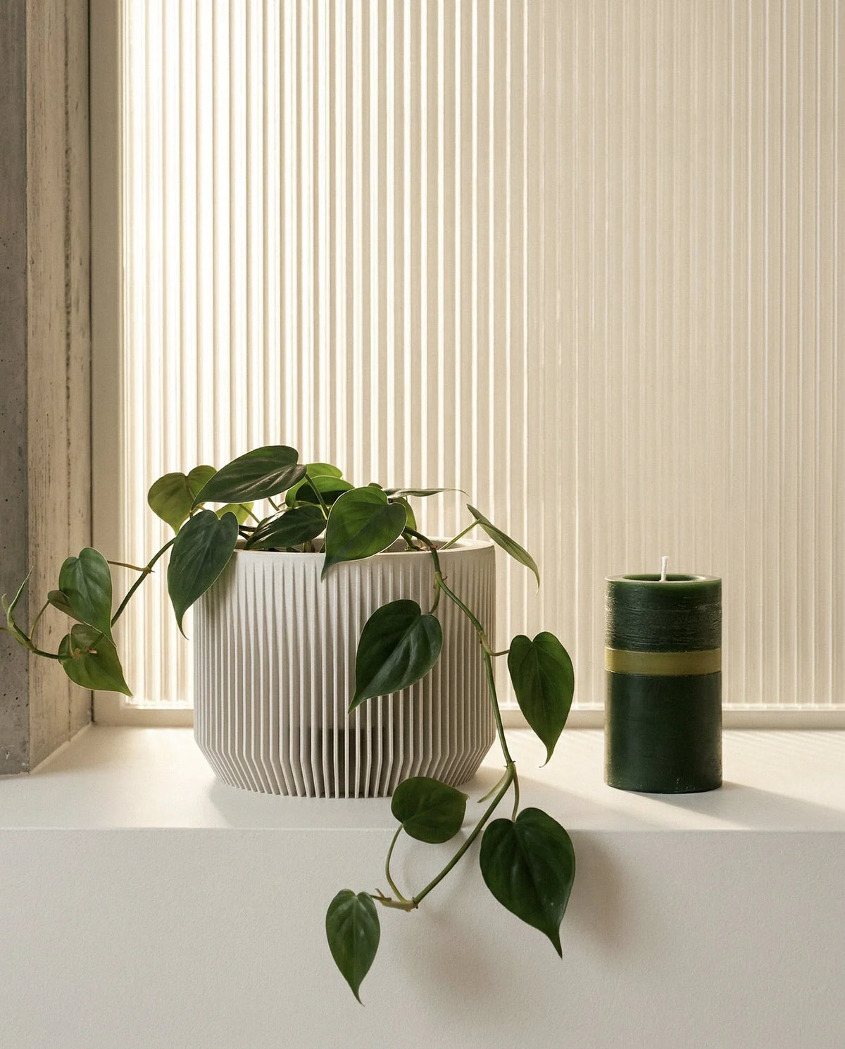mist white praha planter 15cm and candle on a windowsill with blinds in the background