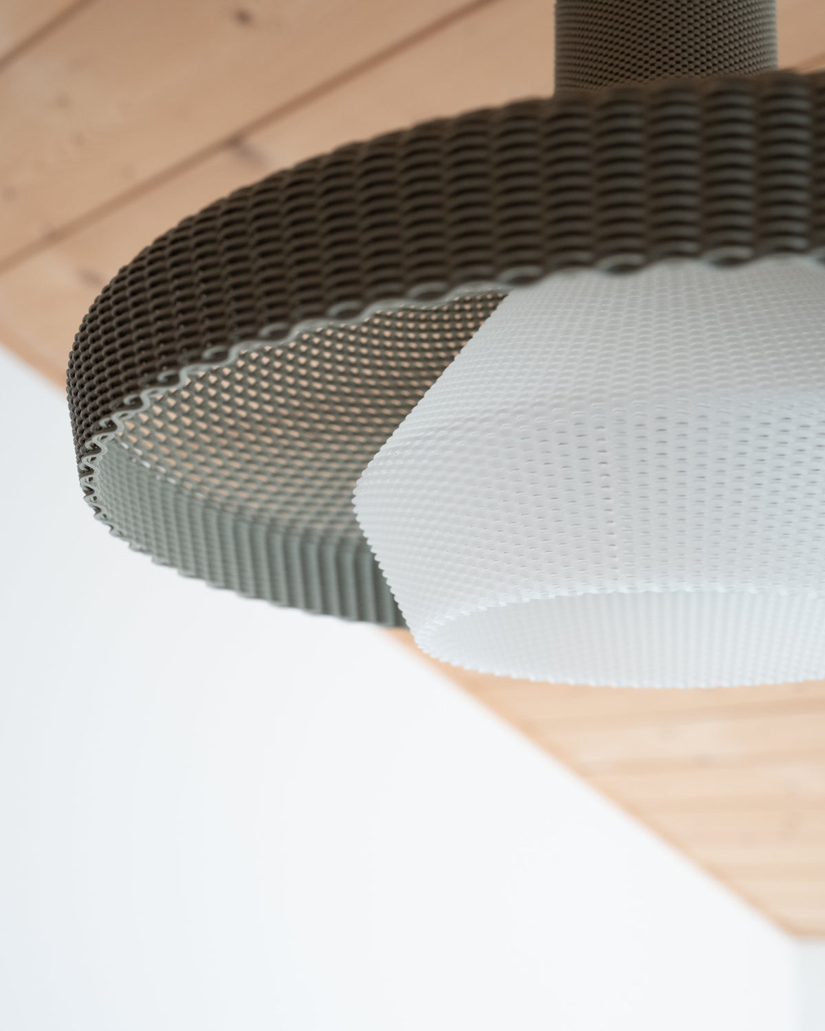 Close up detail of the textured ribbed finish and ciselled lines on the outer shell of the Wove lichen grey pendant light.