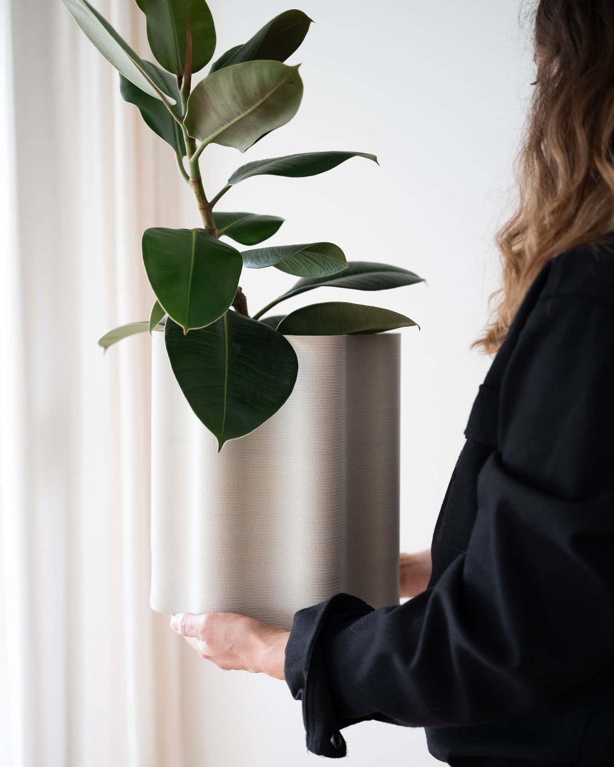 Close-up showing the scale of the Rippled floor planter held in hands, highlighting its large 29cm size and natural wood texture